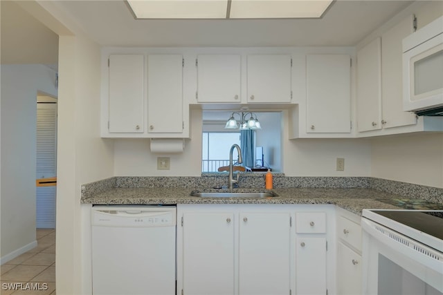 kitchen with light tile patterned floors, white appliances, a sink, and white cabinets