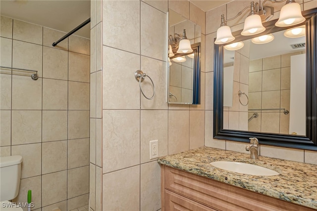 bathroom featuring toilet, visible vents, tile walls, and vanity