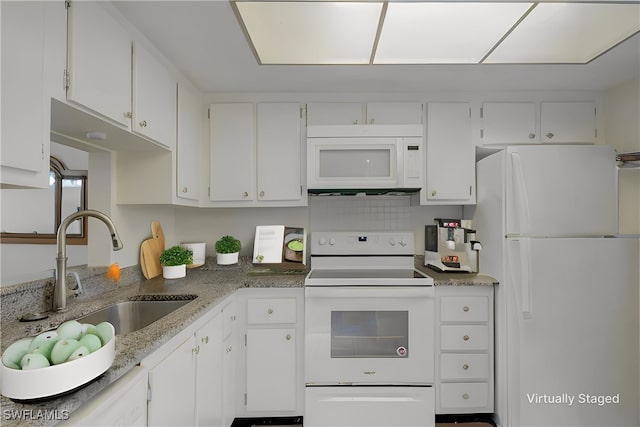 kitchen featuring light stone counters, white appliances, a sink, and white cabinetry