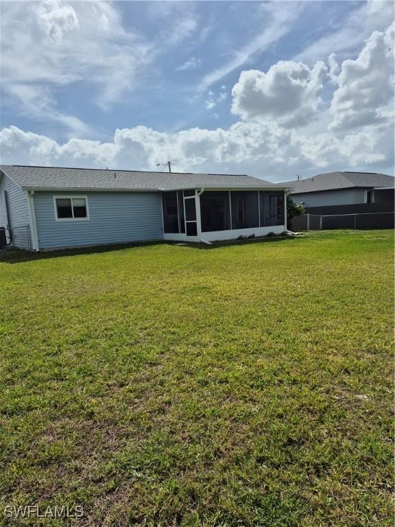 rear view of property with a yard, fence, and a sunroom