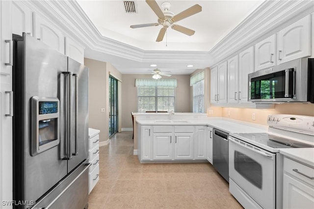 kitchen featuring visible vents, a peninsula, a sink, appliances with stainless steel finishes, and a raised ceiling