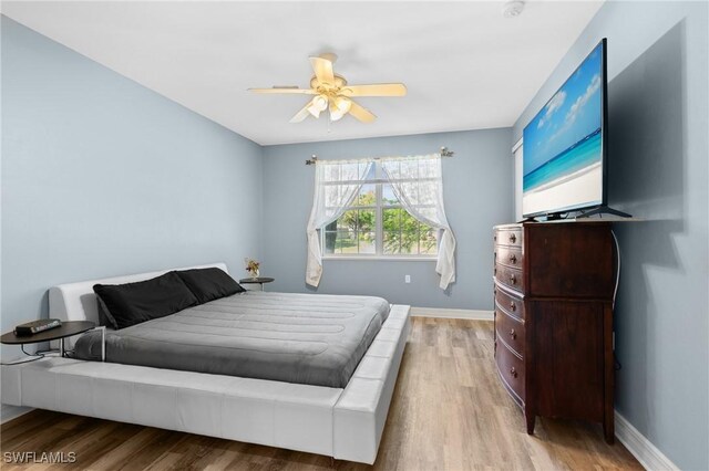 bedroom featuring baseboards, wood finished floors, and a ceiling fan