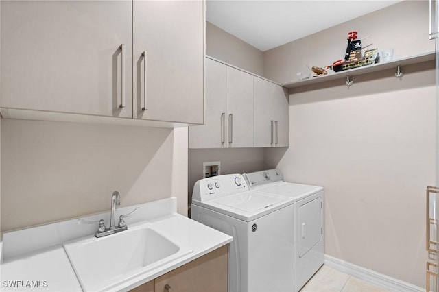 laundry area with a sink, washer and dryer, cabinet space, light tile patterned floors, and baseboards