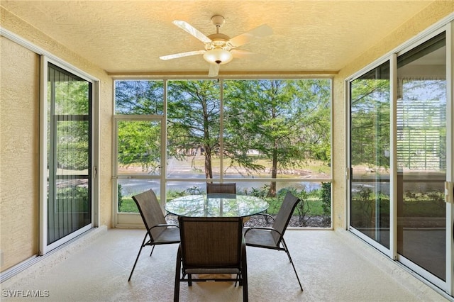 sunroom featuring a ceiling fan and a water view