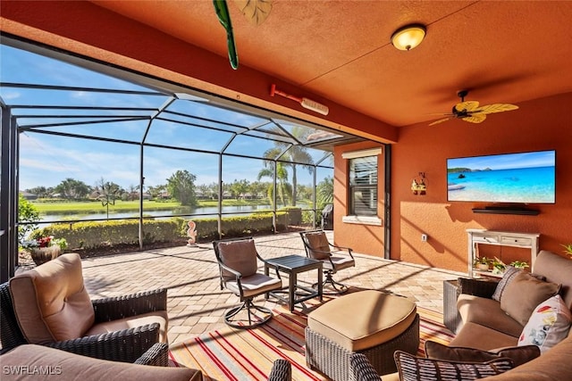 view of patio featuring glass enclosure, a water view, a ceiling fan, and an outdoor hangout area