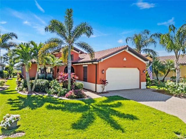 mediterranean / spanish home featuring stucco siding, decorative driveway, a front yard, a garage, and a tiled roof