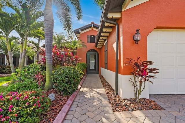 doorway to property with stucco siding and a garage