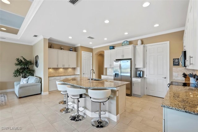 kitchen featuring light stone countertops, a breakfast bar, an island with sink, a sink, and stainless steel appliances