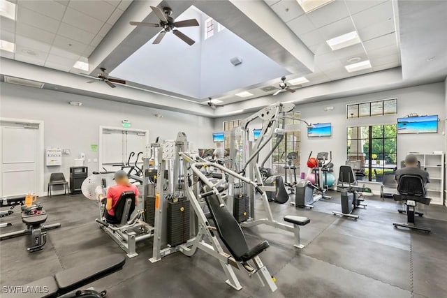 workout area with a drop ceiling, a high ceiling, a raised ceiling, and a ceiling fan