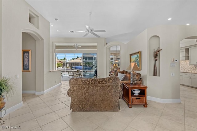 living room with recessed lighting, arched walkways, light tile patterned floors, baseboards, and ceiling fan