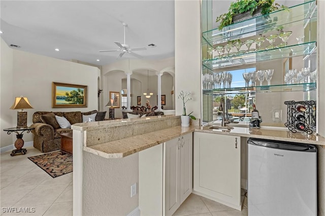 kitchen with open floor plan, fridge, arched walkways, light tile patterned floors, and ceiling fan