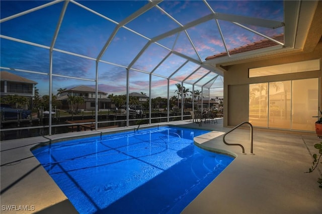 pool at dusk featuring a patio area, an outdoor pool, and a lanai