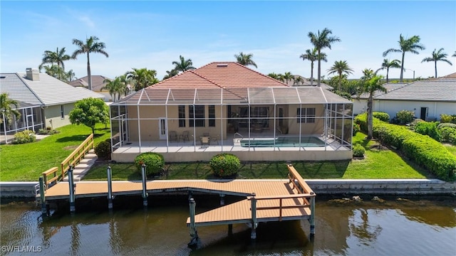 view of dock with glass enclosure, a water view, a lawn, and a patio