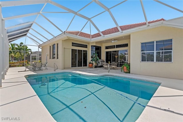 outdoor pool with glass enclosure, a ceiling fan, and a patio