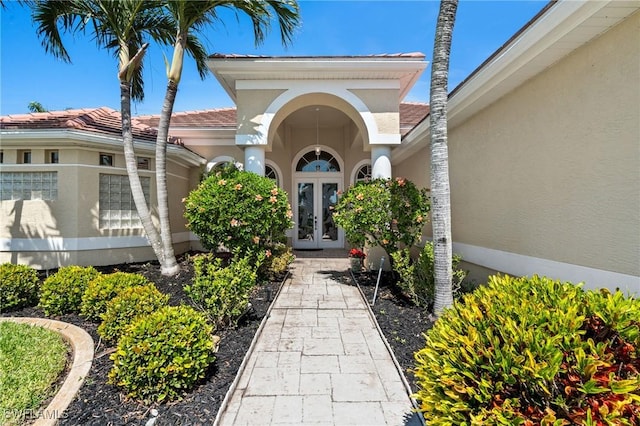 doorway to property with stucco siding, french doors, and a tile roof