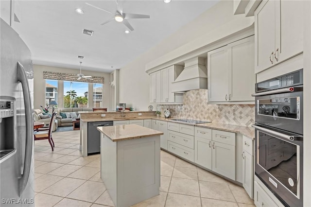 kitchen with a sink, stainless steel appliances, a ceiling fan, and custom range hood