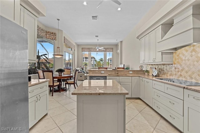 kitchen with a kitchen island, custom range hood, decorative backsplash, black electric cooktop, and a sink