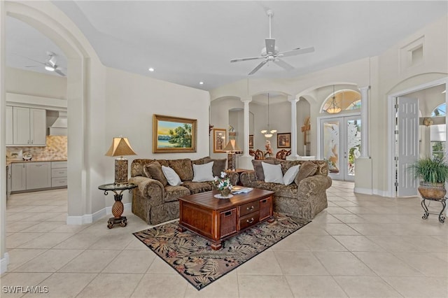 living area featuring french doors, light tile patterned flooring, arched walkways, a ceiling fan, and ornate columns