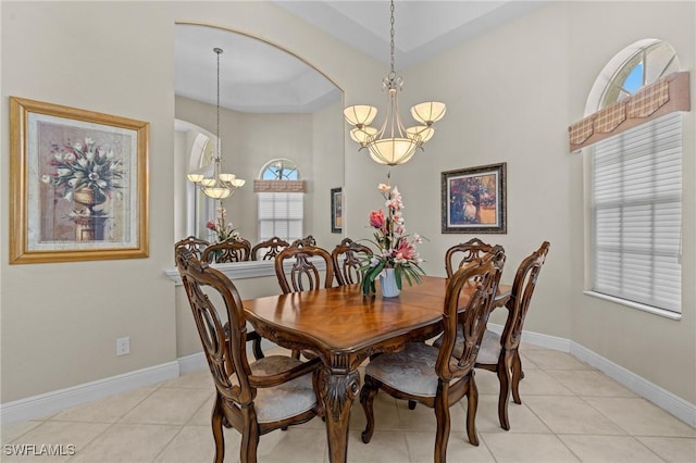 dining room featuring light tile patterned floors, baseboards, arched walkways, and a chandelier