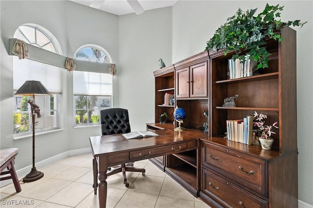 office with a towering ceiling, baseboards, light tile patterned flooring, and a ceiling fan