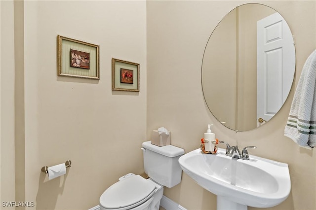 bathroom featuring toilet, baseboards, and a sink