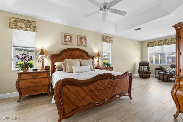 bedroom with visible vents, baseboards, a tray ceiling, and wood tiled floor