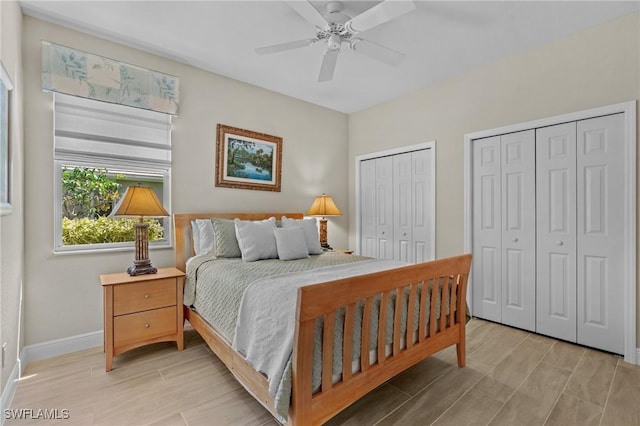 bedroom with ceiling fan, baseboards, two closets, and wood finish floors