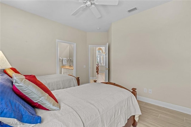 bedroom with a ceiling fan, visible vents, baseboards, light wood-style floors, and connected bathroom