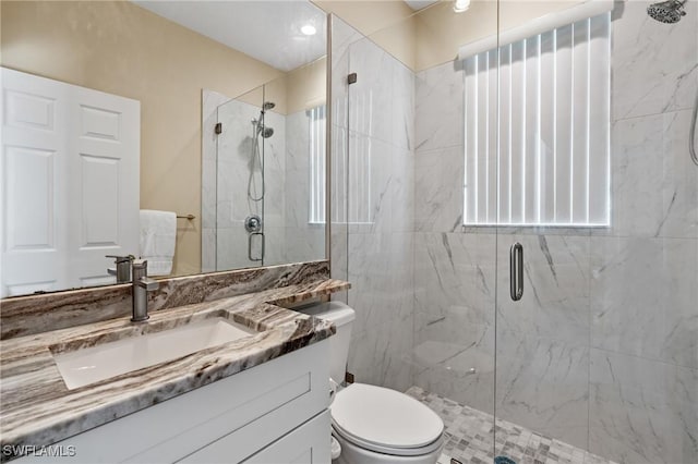 full bath featuring vanity, toilet, a healthy amount of sunlight, and a marble finish shower