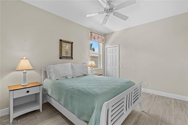 bedroom with ceiling fan, baseboards, a closet, and wood tiled floor