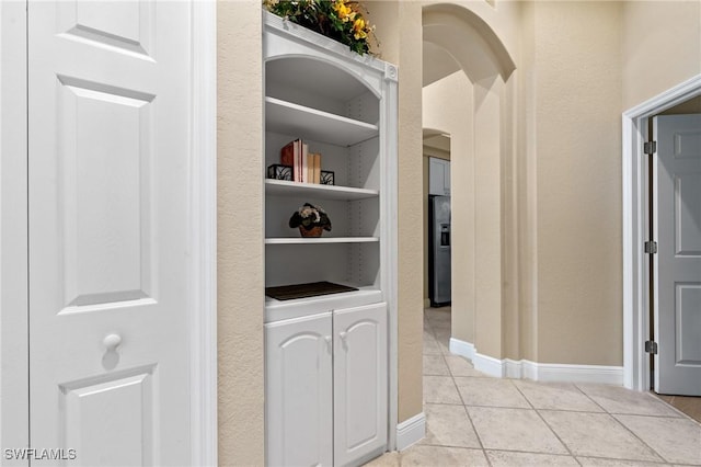 corridor with built in features, baseboards, and light tile patterned flooring