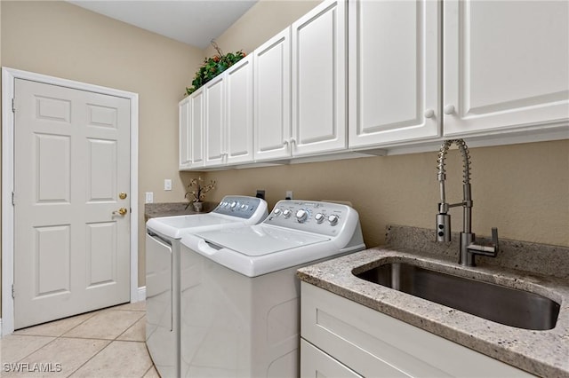 laundry area featuring a sink, cabinet space, light tile patterned floors, and washing machine and clothes dryer