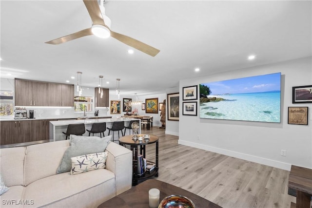 living area featuring light wood-type flooring, ceiling fan, baseboards, and recessed lighting