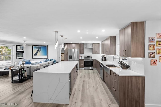 kitchen with stainless steel appliances, a large island, modern cabinets, and light wood-style floors