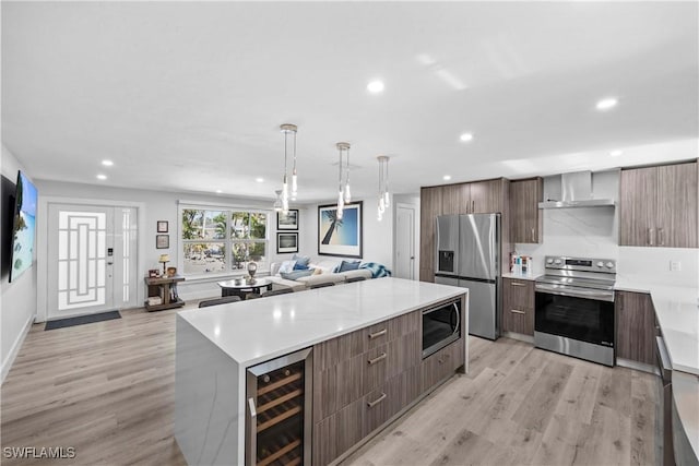 kitchen with beverage cooler, stainless steel appliances, wall chimney exhaust hood, and modern cabinets