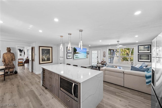 kitchen featuring light wood-style flooring, recessed lighting, a kitchen island, stainless steel microwave, and modern cabinets