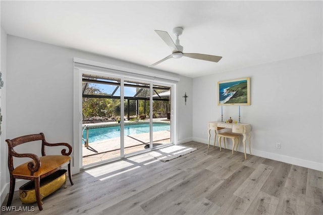 living area featuring baseboards, a ceiling fan, a sunroom, wood finished floors, and a swimming pool