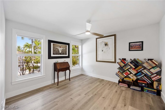 living area with wood finished floors, a ceiling fan, and baseboards