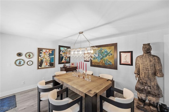 dining room with an inviting chandelier, light wood-style flooring, and baseboards