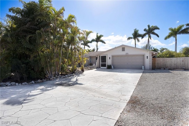 ranch-style house featuring stucco siding, driveway, an attached garage, and fence