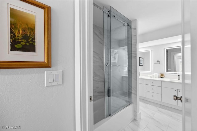 full bath featuring marble finish floor, double vanity, bath / shower combo with glass door, and a sink