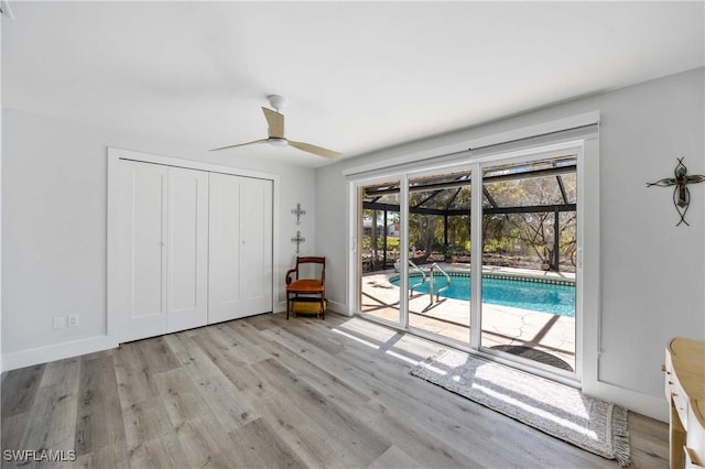 interior space featuring light wood-type flooring, a sunroom, ceiling fan, and baseboards