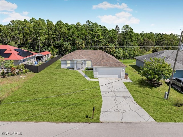 view of front of property with an attached garage, driveway, a forest view, and a front yard