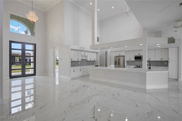 interior space featuring marble finish floor, a healthy amount of sunlight, ornamental molding, and ceiling fan with notable chandelier