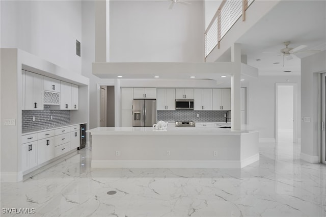 kitchen with marble finish floor, white cabinetry, stainless steel appliances, and a ceiling fan