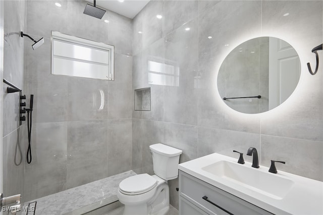 bathroom with vanity, tile walls, toilet, and tiled shower