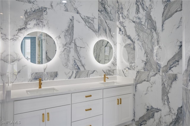 full bathroom featuring double vanity, stone wall, and a sink