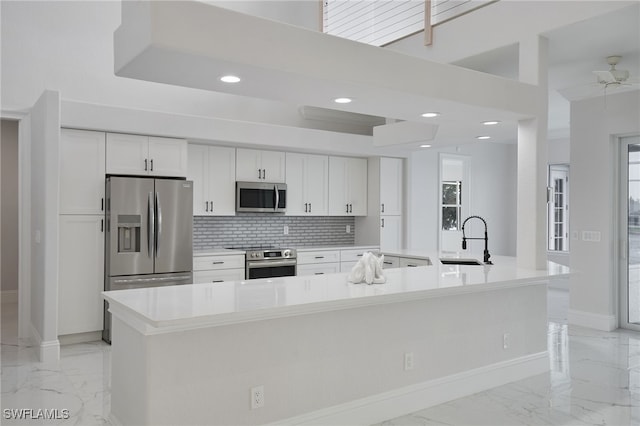 kitchen featuring marble finish floor, appliances with stainless steel finishes, white cabinetry, and a sink