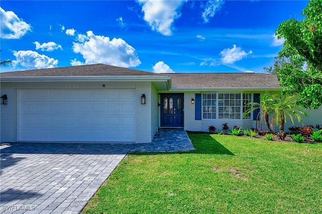 single story home with a garage, brick siding, decorative driveway, and a front yard