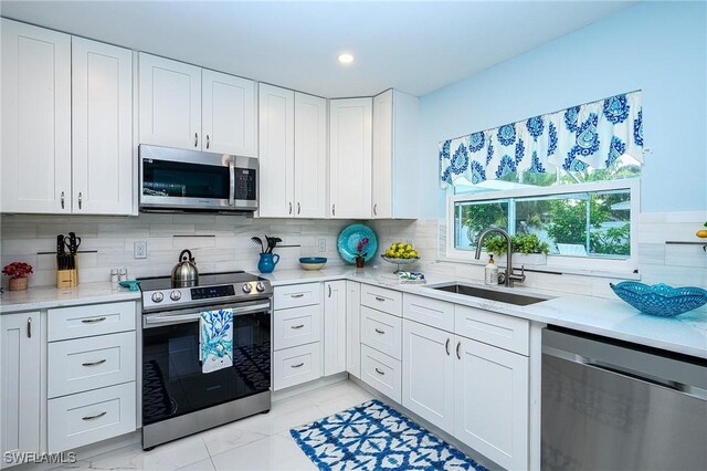 kitchen with decorative backsplash, appliances with stainless steel finishes, white cabinets, and a sink